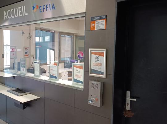 Guichet d'accueil vitré EFFIA équipé de panneaux d'information et d'un interphone d'assistance.
