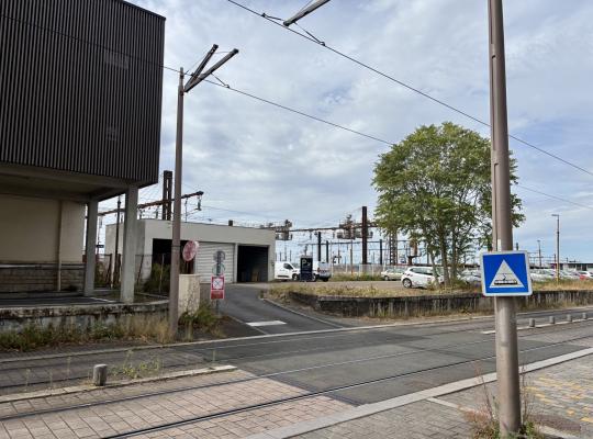 Voie d'accès au parking extérieur située à proximité des voies ferrées et de la ligne de tramway.