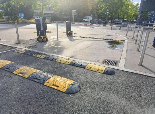Barrière de sortie, borne de paiement et ralentisseurs en caoutchouc sur la voie de circulation.