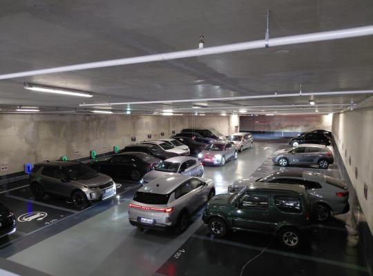 Vue en hauteur d'un niveau de parking souterrain avec allée de circulation et places équipées de bornes de recharge électrique.