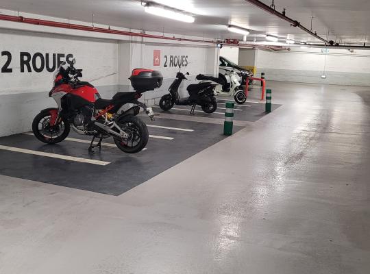 Zone de stationnement réservée aux deux-roues (motos et scooters) avec signalétique murale dédiée dans un parking couvert.