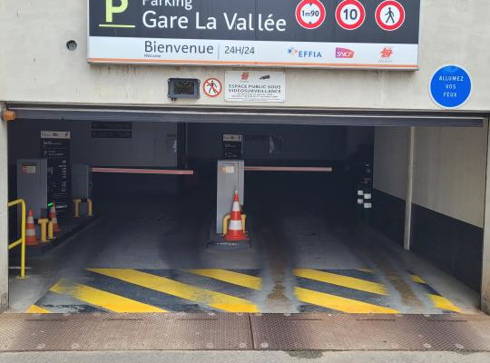 Entrée du parking EFFIA Gare La Vallée avec panneau d'affichage des consignes, limite de hauteur à 1,90 m et bornes d'accès.