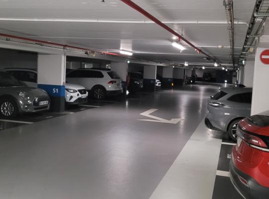 Allée de circulation et places de stationnement numérotées au niveau S1 d'un parking souterrain.