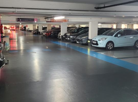 Allée de circulation et emplacements de stationnement numérotés au niveau -2 d'un parking souterrain.