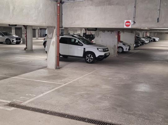 Places de stationnement numérotées au sol le long de piliers de soutien dans un parking souterrain.