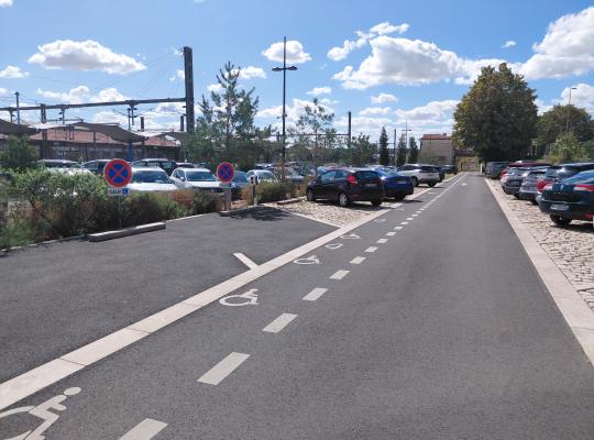 Emplacements de stationnement réservés aux personnes à mobilité réduite (PMR) signalés par un marquage au sol et des panneaux.