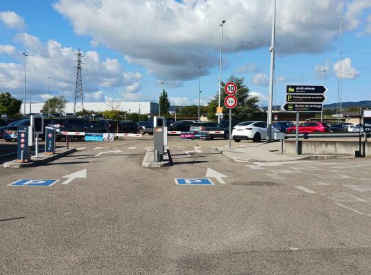 Voies d'accès au parking P1 équipées de bornes de péage automatiques, de barrières et de panneaux de signalisation.