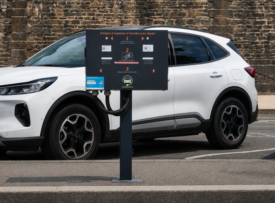 Panneau d'instructions pour la recharge des véhicules électriques devant un véhicule en stationnement.