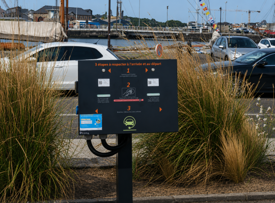 Panneau d'instructions pour la recharge des véhicules électriques situé au bord du port.