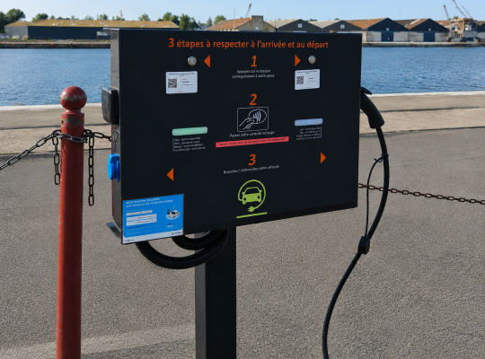 Borne de recharge pour véhicules électriques installée sur le quai face au bassin.