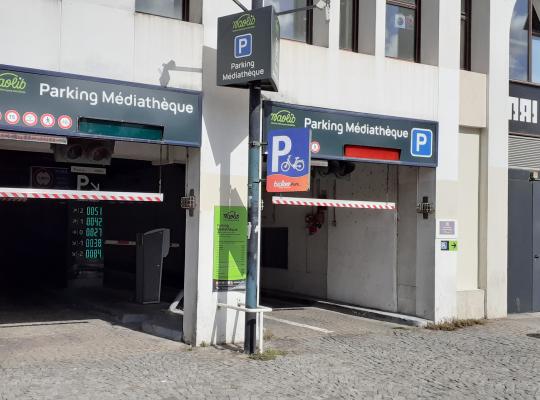 Entrée extérieure du Parking Médiathèque Naolib indiquant les voies d'accès, barrières de hauteur et panneau d'information à côté du Musée-Atelier de l'Imprimerie.