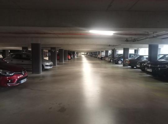 Vue d'ensemble des places de stationnement alignées le long d'une allée dans un parking couvert.