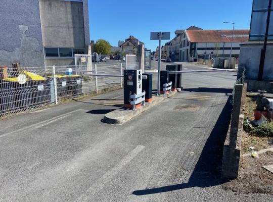 Zone de sortie du parking dotée de bornes à tickets et de barrières levantes s'ouvrant sur la rue.