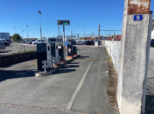 Voie d'accès au parking équipée de bornes de contrôle et d'un panneau d'affichage indiquant les places libres.