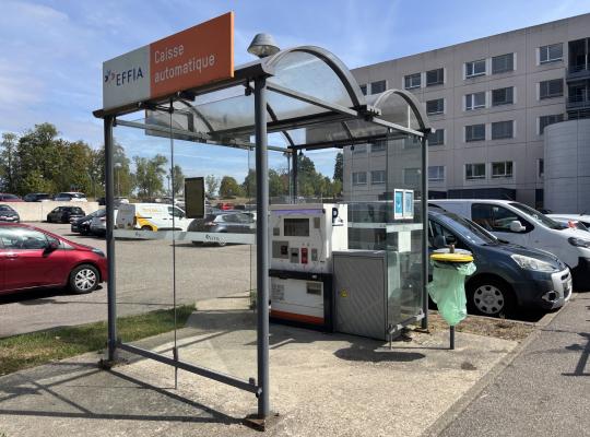 Station de paiement automatique EFFIA protégée sous un abri vitré sur le parking extérieur.