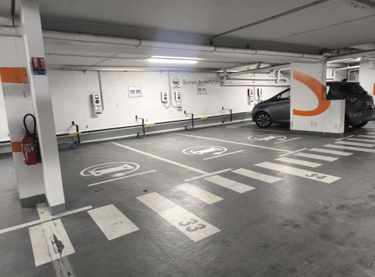 Places de stationnement réservées à la recharge des véhicules électriques, équipées de bornes murales et d'un marquage dédié.