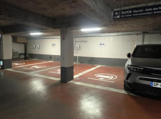 Emplacements au sol rouge réservés à la recharge des véhicules électriques dans le parking souterrain.