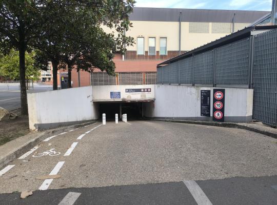Rampe d'accès menant à l'entrée du parking souterrain Léo Ferré avec signalisation routière et marquage vélo.