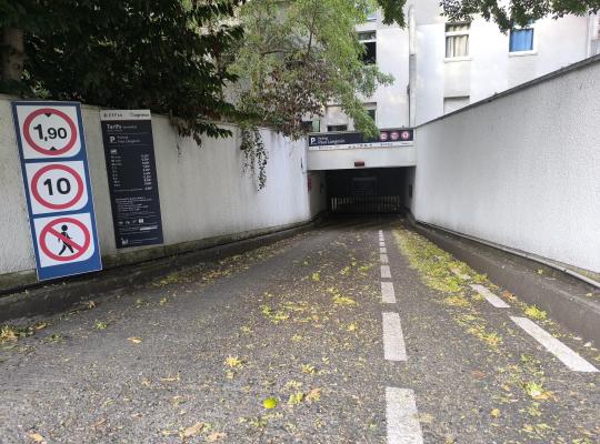 Rampe d'accès descendant vers le parking souterrain Paul Langevin, encadrée par la signalisation des tarifs et de la hauteur maximale.