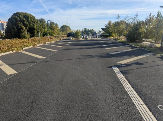 Emplacements de stationnement extérieurs tracés en épi le long de la voie de circulation.