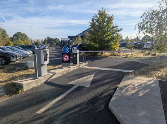 Zone de sortie équipée d'une borne de paiement, d'un panneau de signalisation et d'une barrière automatique.