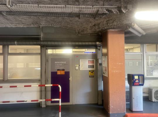 Entrée de la boutique EFFIA en sous-sol avec porte d'accueil, grille de protection et borne de paiement Skidata.