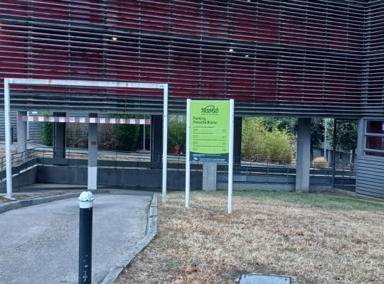 Entrée du parking couvert Naolib / EFFIA Fresche Blanc avec rampe d'accès, gabarit de hauteur et panneaux de signalisation.