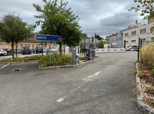 Zone de sortie du parking matérialisée par un panneau bleu « SORTIE », des bornes de validation et une barrière automatique.