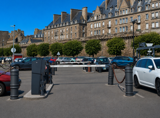 Voies de sortie du parking équipées de bornes de contrôle et de barrières automatiques face aux remparts.