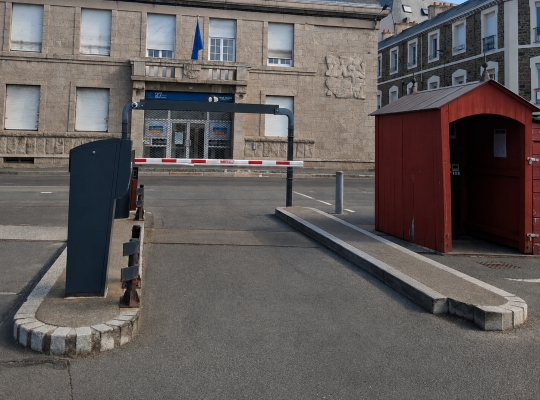 Voie de sortie contrôlée par une barrière automatique à côté d'un chalet abritant la caisse de paiement.