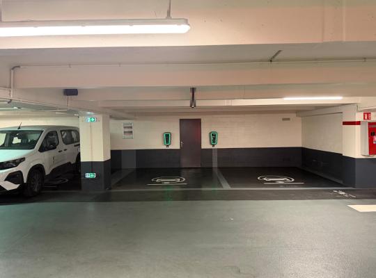 Emplacements réservés à la recharge des véhicules électriques équipés de bornes murales rétroéclairées en vert.