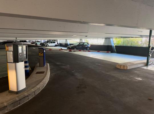 Voie de sortie dans un parking couvert avec borne de validation du ticket et barrière levante.