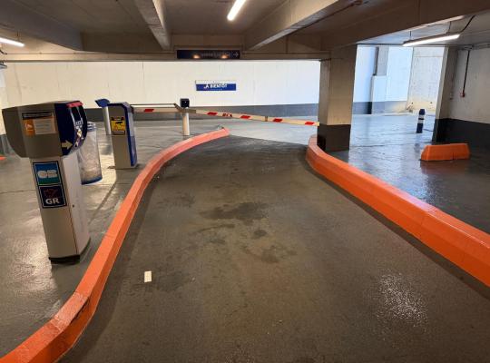 Borne de paiement par carte bancaire et barrière de sortie dans une voie du parking souterrain.
