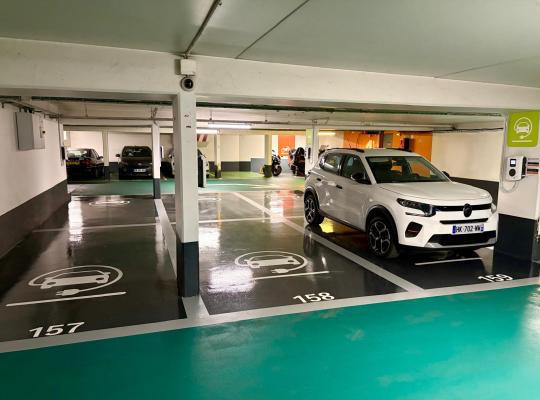 Places de stationnement réservées à la recharge des véhicules électriques, numérotées au sol avec bornes murale.