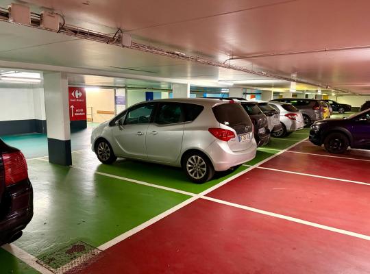 Allée de circulation et emplacements de parking colorés avec signalétique menant vers l'accès au magasin Carrefour.