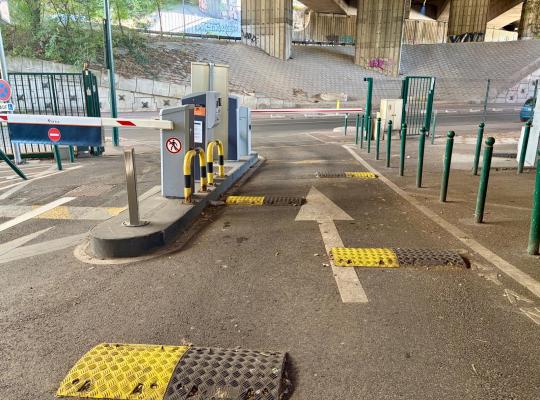 Borne d'accès avec barrière levante et signalétique EFFIA à l'entrée d'un parking couvert sous pont.