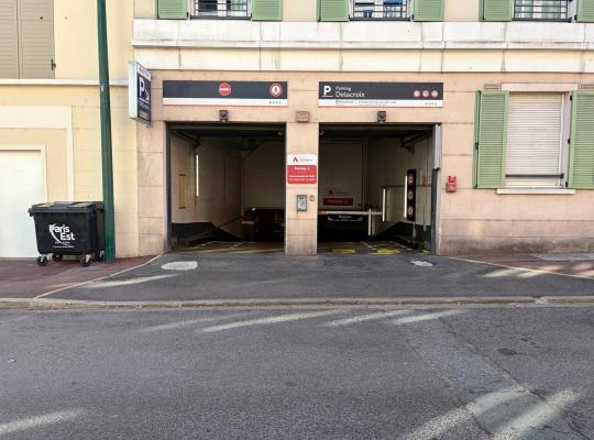 Façade de l'entrée du parking couvert Delacroix avec double voie d'accès et panneau de signalisation.
