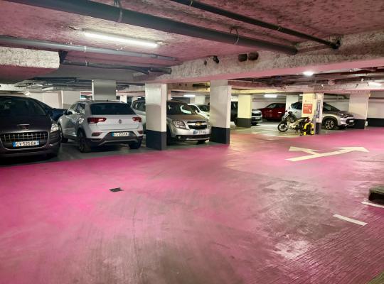 Sol peint en rose, fléchage d'orientation et véhicules stationnés dans un niveau souterrain du parking Delacroix.