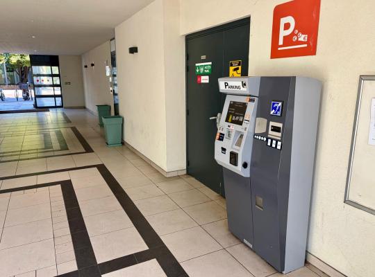 Caisse automatique de paiement par carte et espèces installée dans le hall d'accès piéton du parking.