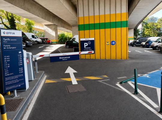 Totem des tarifs EFFIA et borne d'accès avec barrière fermée devant une place PMR au parking M. Échangeur.