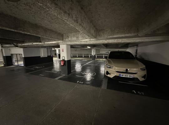 Emplacements de stationnement numérotés au sol et extincteur mural dans un niveau souterrain de parking.