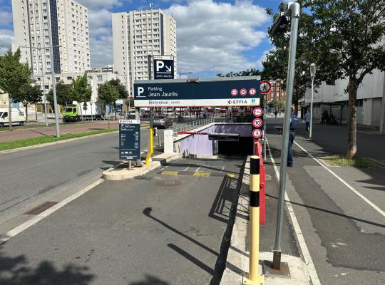 Rampe d'accès extérieure du parking Jean Jaurès avec totems d'information des tarifs et barrières automatiques.