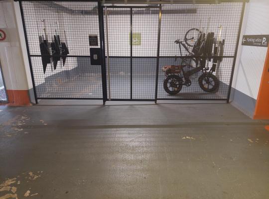 Local à vélos sécurisé et fermé par une grille métallique dans un parking