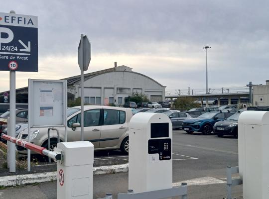 Entrée du parking extérieur avec borne de ticket EFFIA et panneau d'affichage