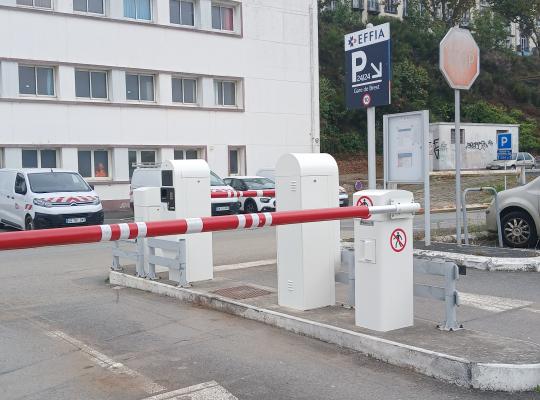 Barrière de sortie du parking avec bornes de passage devant le bâtiment.