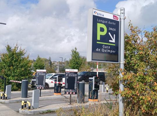 Voie d'accès au parking longue durée avec bornes, barrières et panneau EFFIA