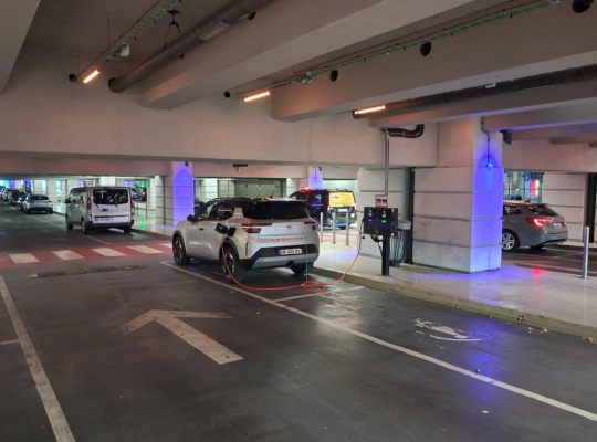 Véhicule en cours de recharge sur un emplacement dédié à l'intérieur du parking couvert.