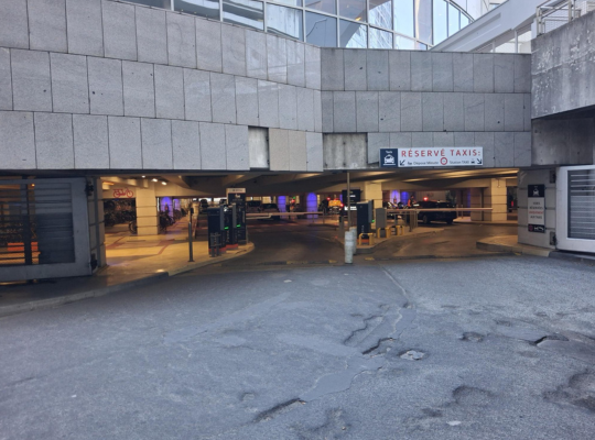 Portail d'accès sous l'immeuble avec signalisation dédiée aux taxis et au dépose-minute.