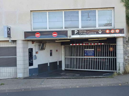 Entrée du parking Orsay Centre fermée par une grille roulante métallique.