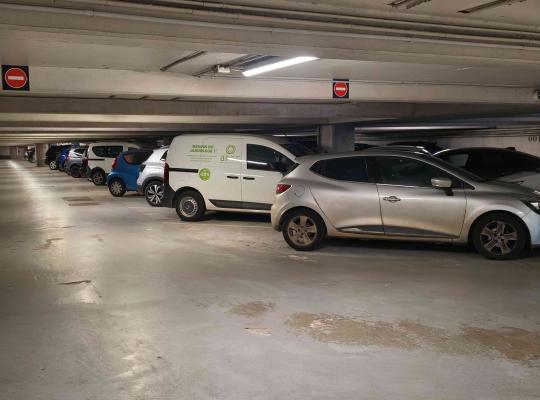 Rangée de véhicules stationnés dans un parking souterrain éclairé.